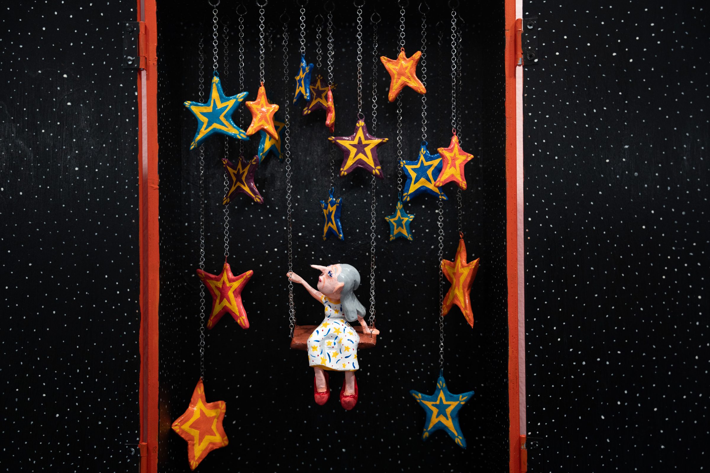 A figure swinging among hanging painted stars