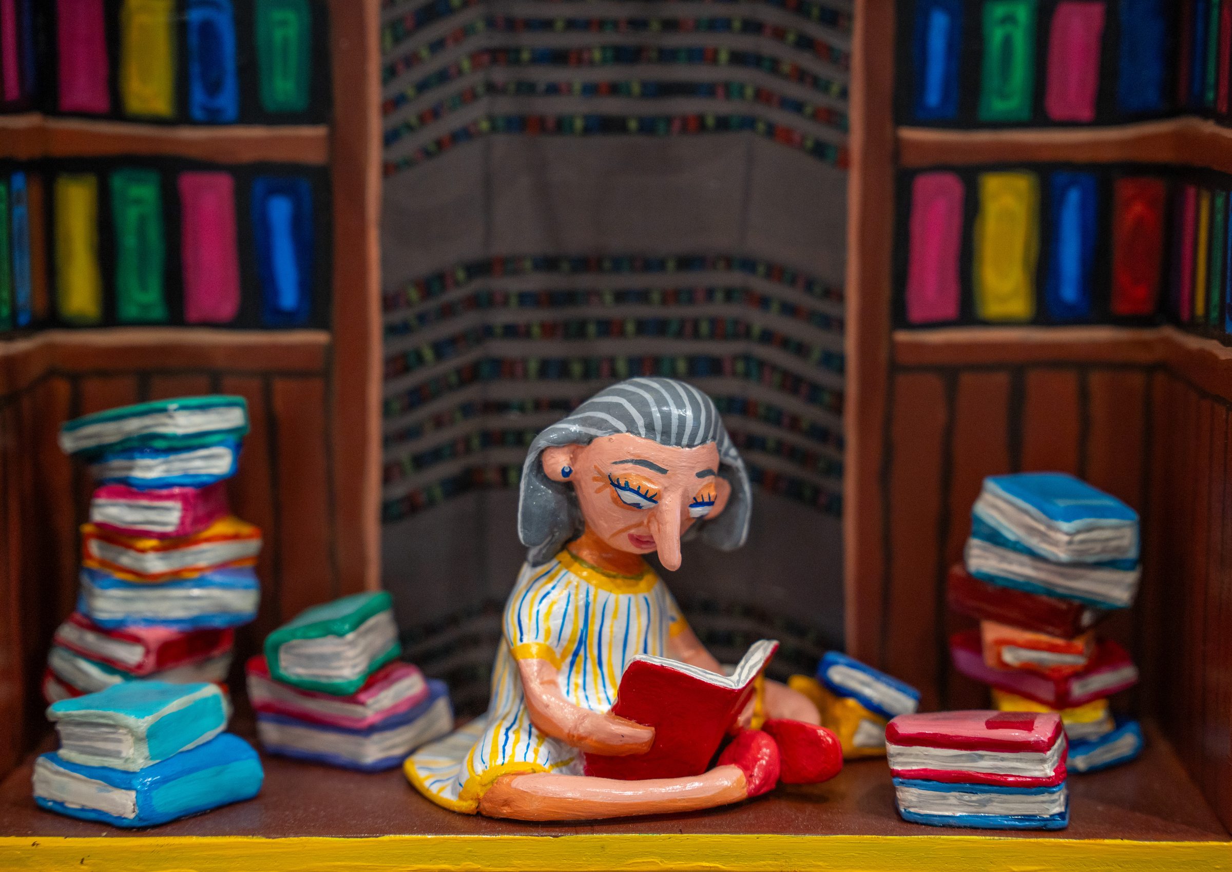 A figure reading among towering stacks of books